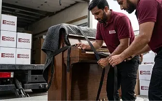 E House Mover team securing a piano for safe transport in Dubai.