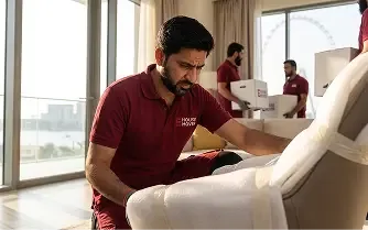 Mover wrapping and protecting a sofa during home relocation in Dubai.