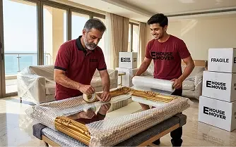 Movers carefully wrapping fragile furniture during home relocation in Dubai.