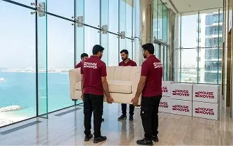 Movers carrying sofa during apartment relocation in a Dubai high-rise.