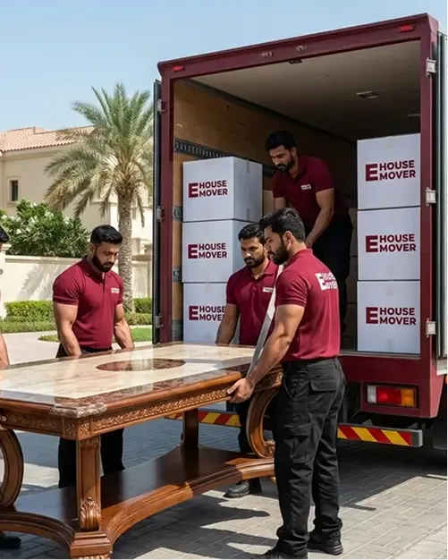 Movers loading a dining table into a truck during villa relocation in Dubai.
