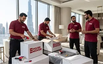 Movers packing boxes during a home relocation in a Dubai apartment.