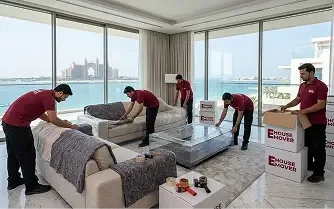 Movers protecting and packing furniture inside a luxury Dubai apartment.