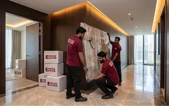Movers protecting and wrapping furniture inside a luxury Dubai apartment.