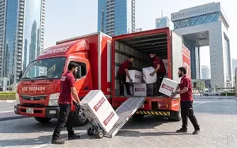 Movers unloading packed boxes from a truck during relocation in Dubai.