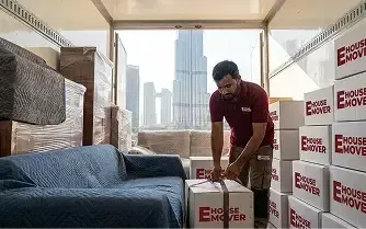 Movers unloading packed boxes from a truck during relocation in Dubai.