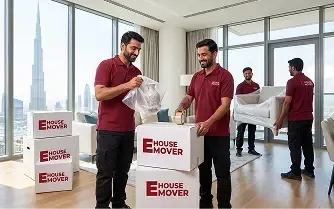 Movers wrapping and packing kitchen items during relocation in Dubai.