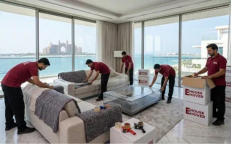 Movers wrapping and packing kitchen items during relocation in Dubai.