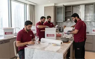Movers wrapping and packing kitchen items during relocation in Dubai.